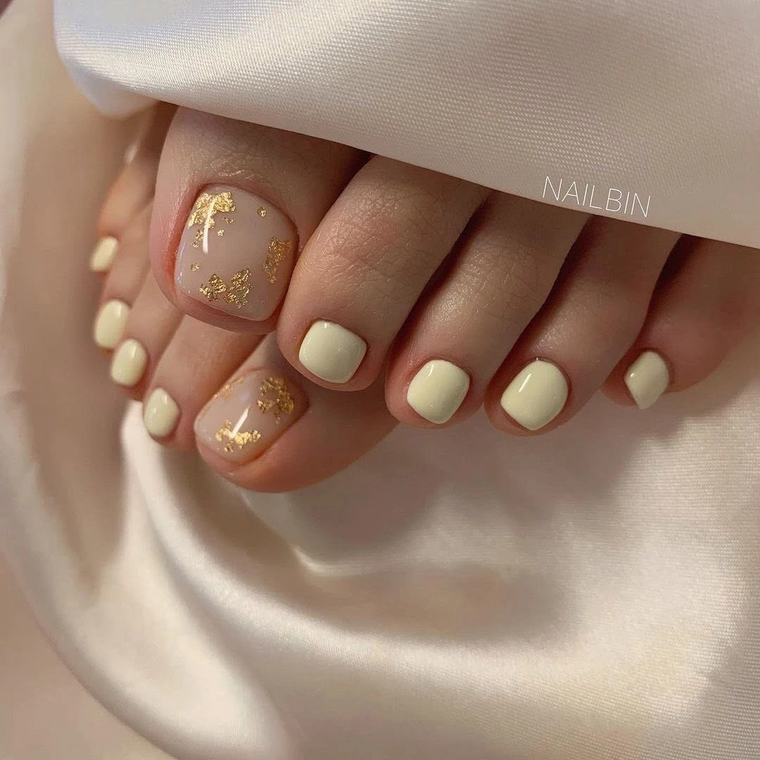 august toe nails 2026 Soft Ivory Pedicure with Delicate Gold Foil Accents