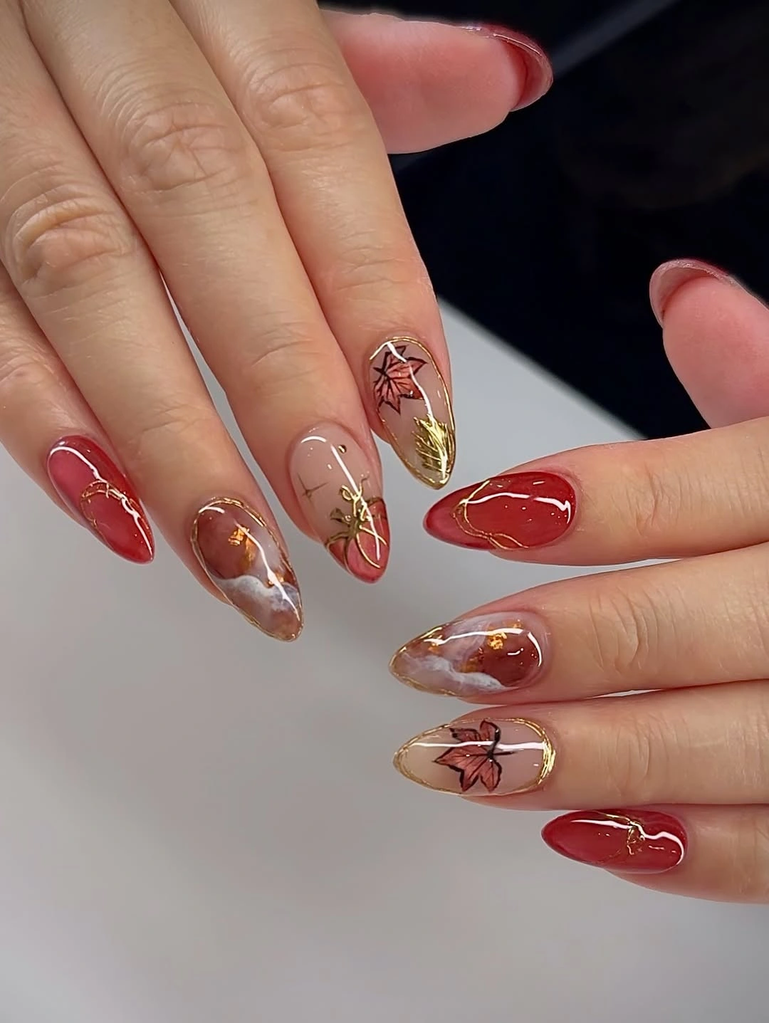Fall manicure 2026 Red And Gold Almond Manicure With Leaf Detail