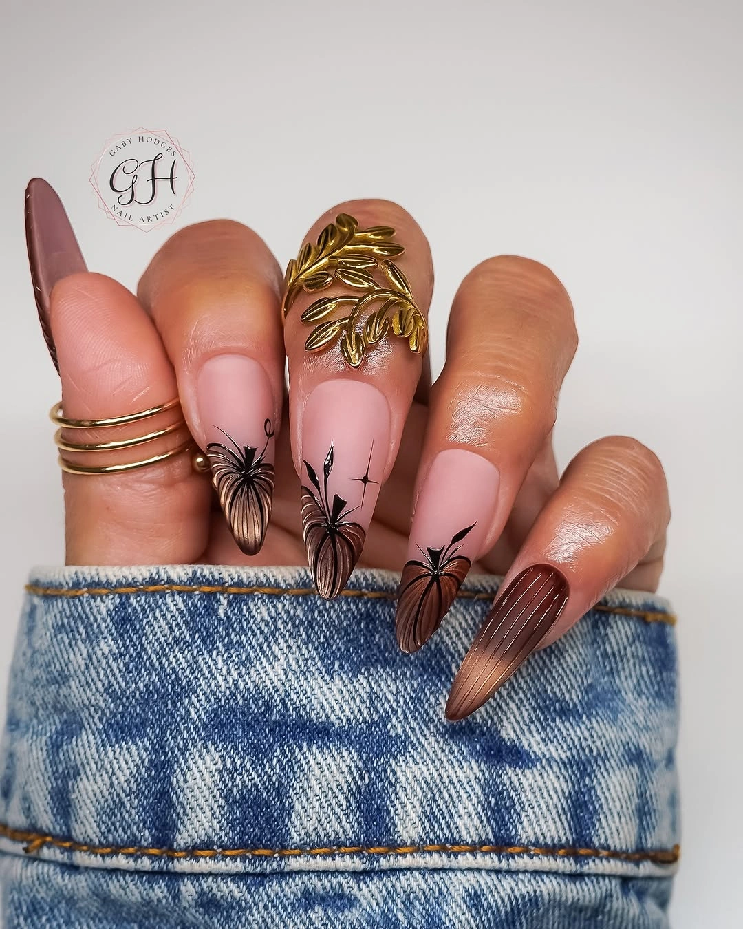 Long pointed pink and brown nails with black floral and gold details
