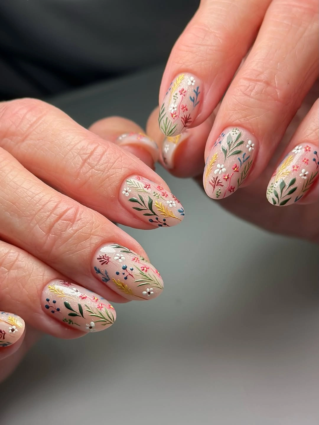 Medium almond nails with delicate muted flowers and leafy autumn strokes