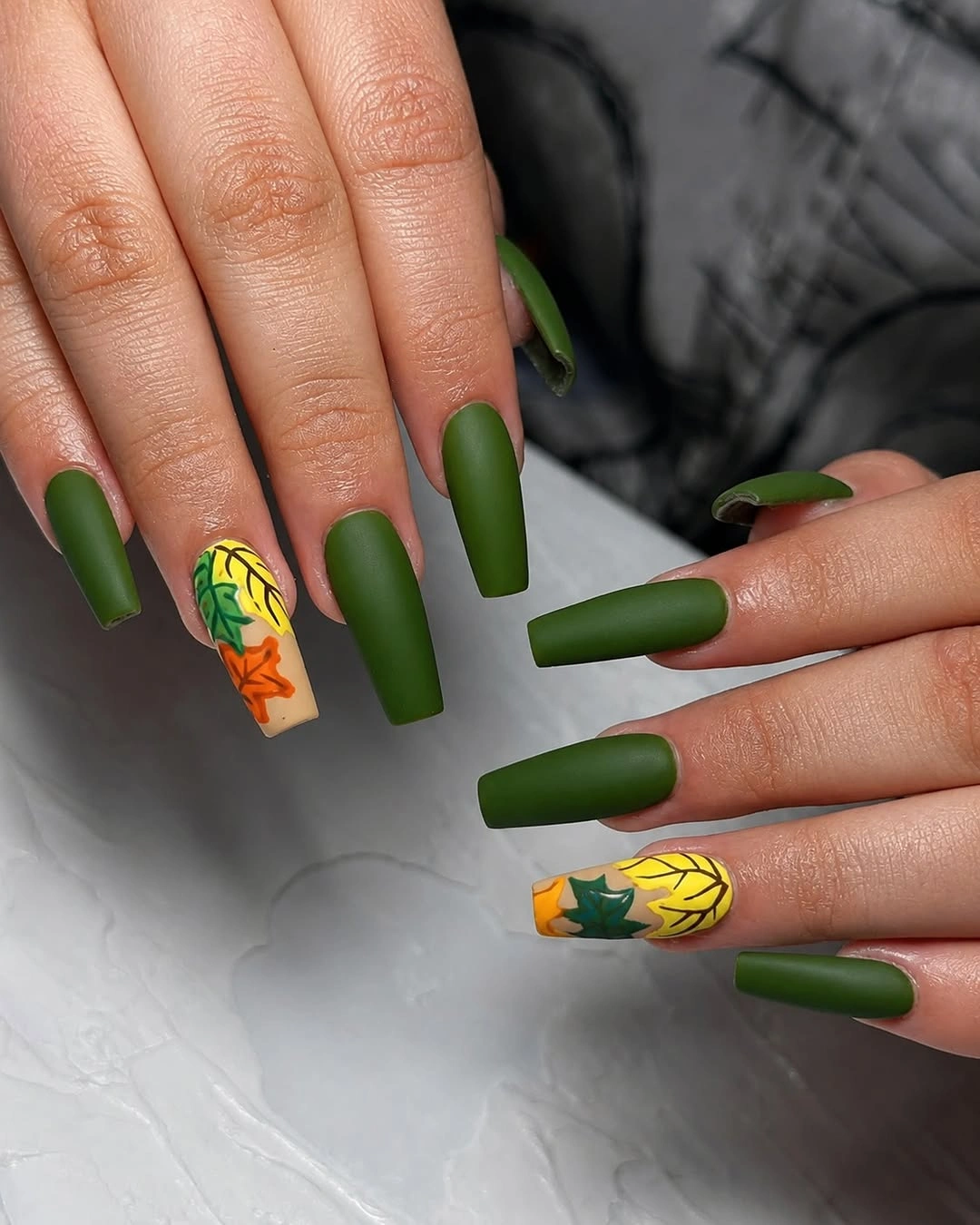 Long square matte green nails with bright yellow and orange motifs