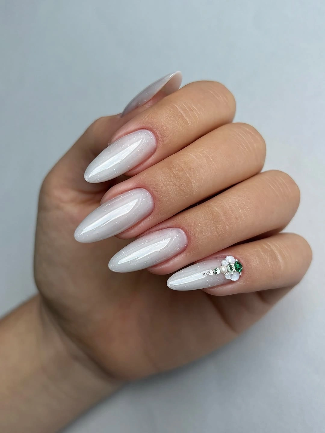Long almond pearly white nails with one small jeweled floral accent