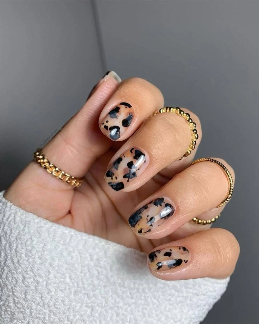 Short rounded nude nails with black and brown organic autumn spots