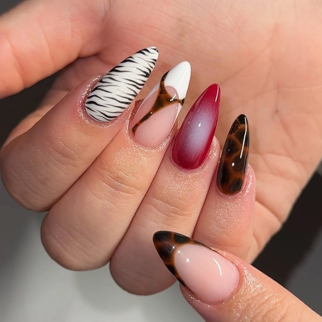 Long almond nails with zebra, tortoiseshell, pink, and red accents