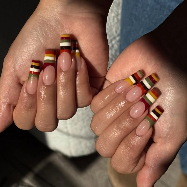 Medium neutral nails with stacked orange brown red and green stripes