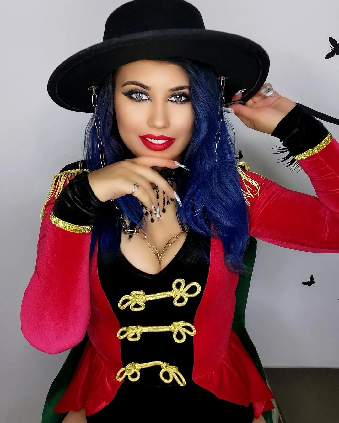 Gothic circus ringmaster costume with black hat, red sleeves, and gold closures