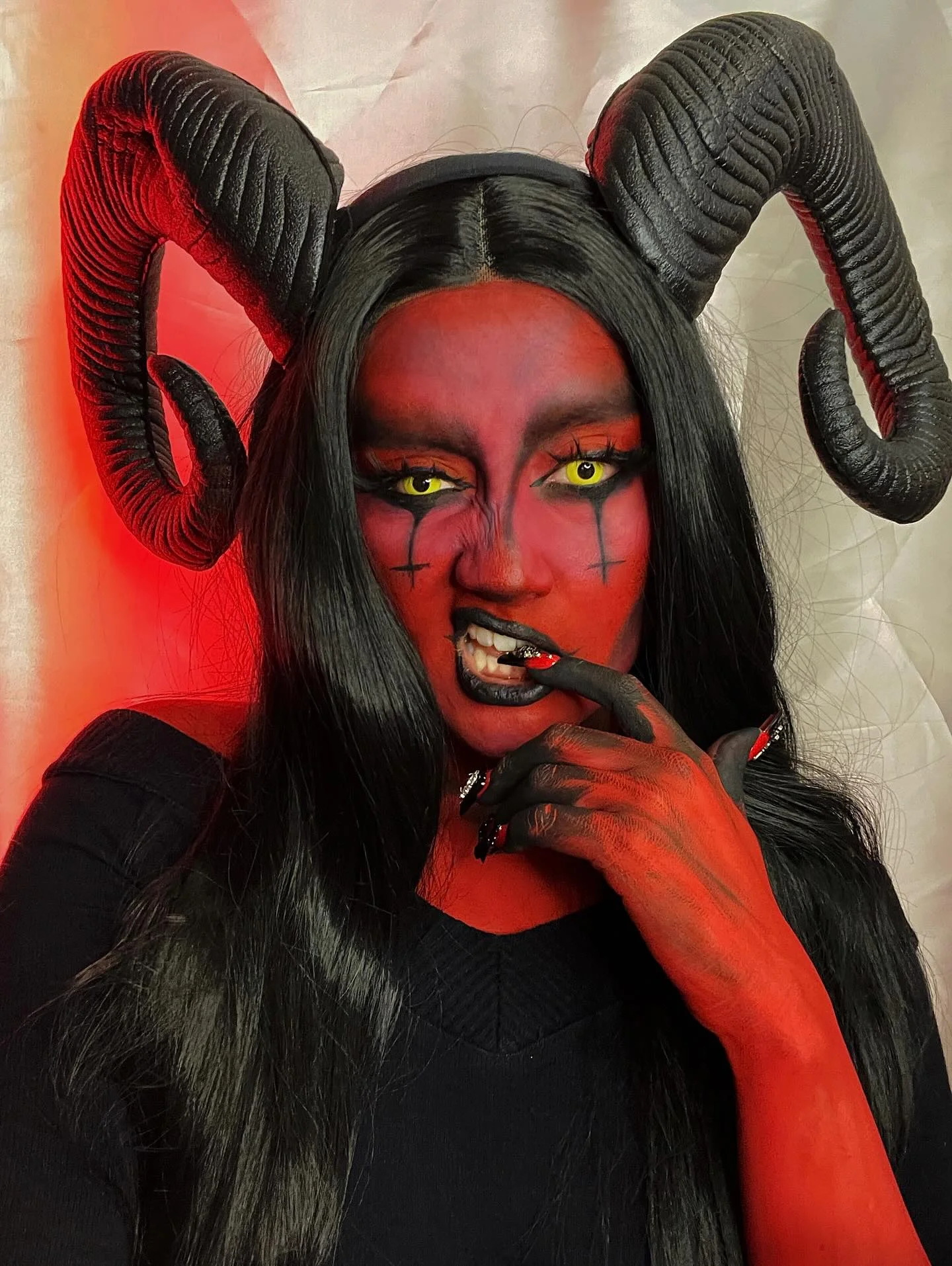 Horned red demon Halloween character with black hair and dramatic makeup