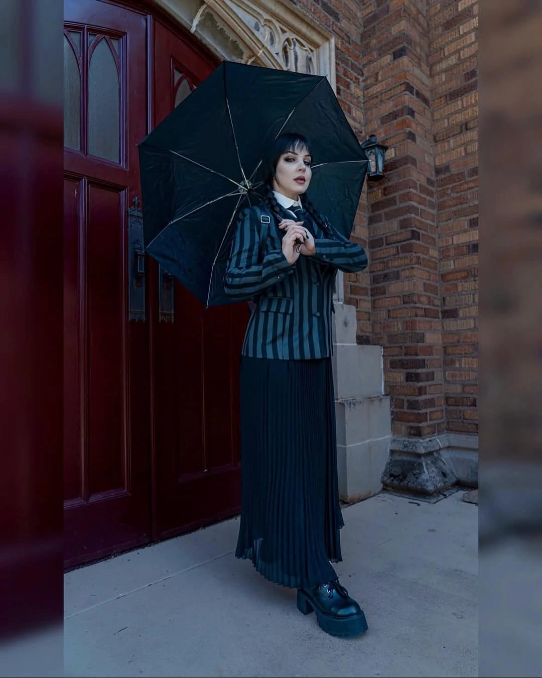 Wednesday Addams costume with striped suit, white collar, braids, and umbrella