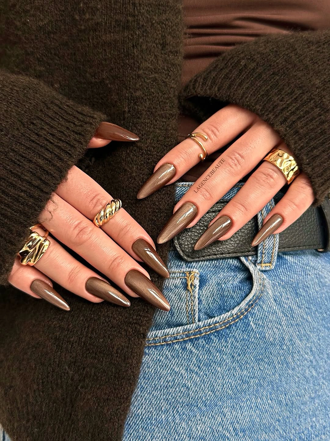 Short glossy brown nails with one pale confetti accent