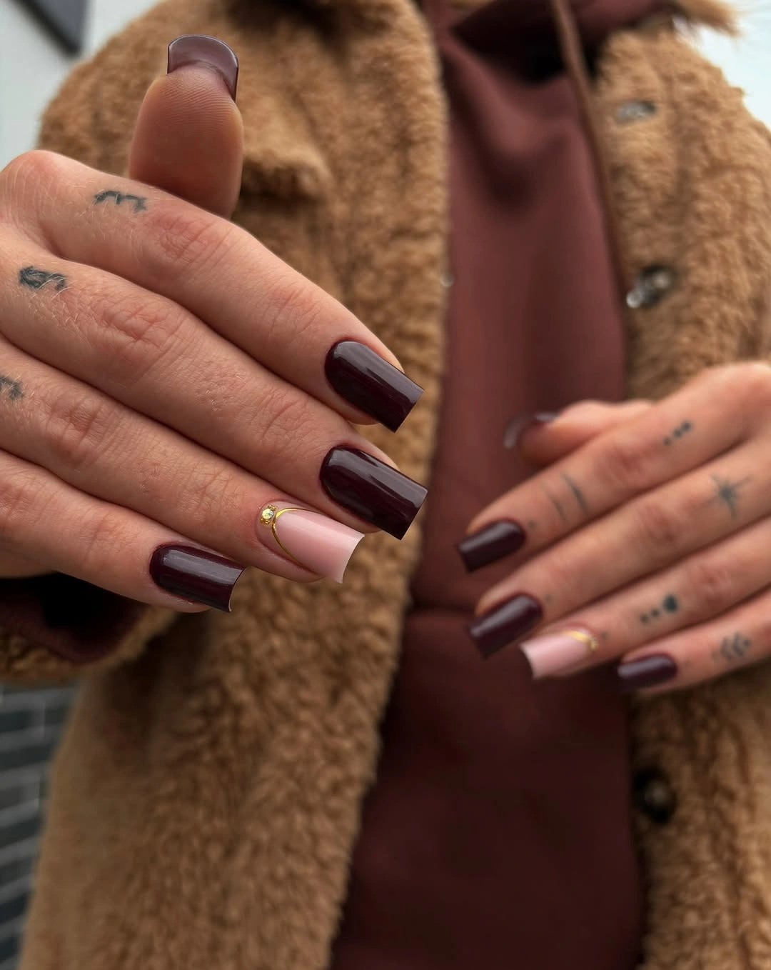 Glossy warm brown almond nails styled with denim and knitwear