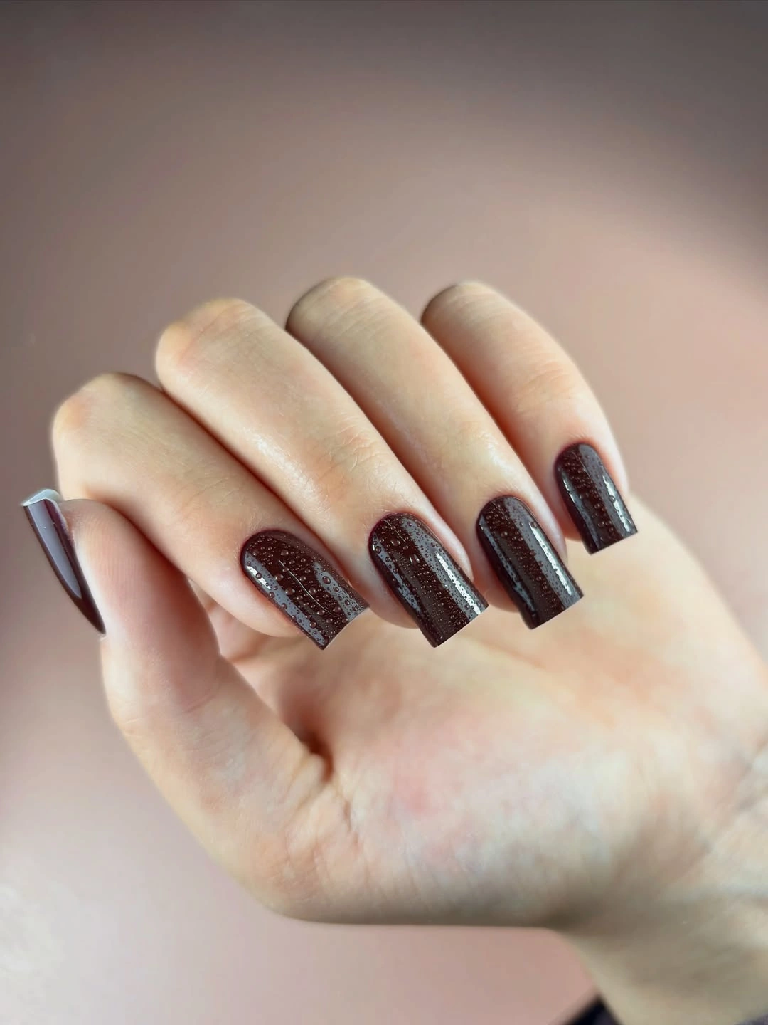 Medium almond nails in warm glossy brown beside knitwear