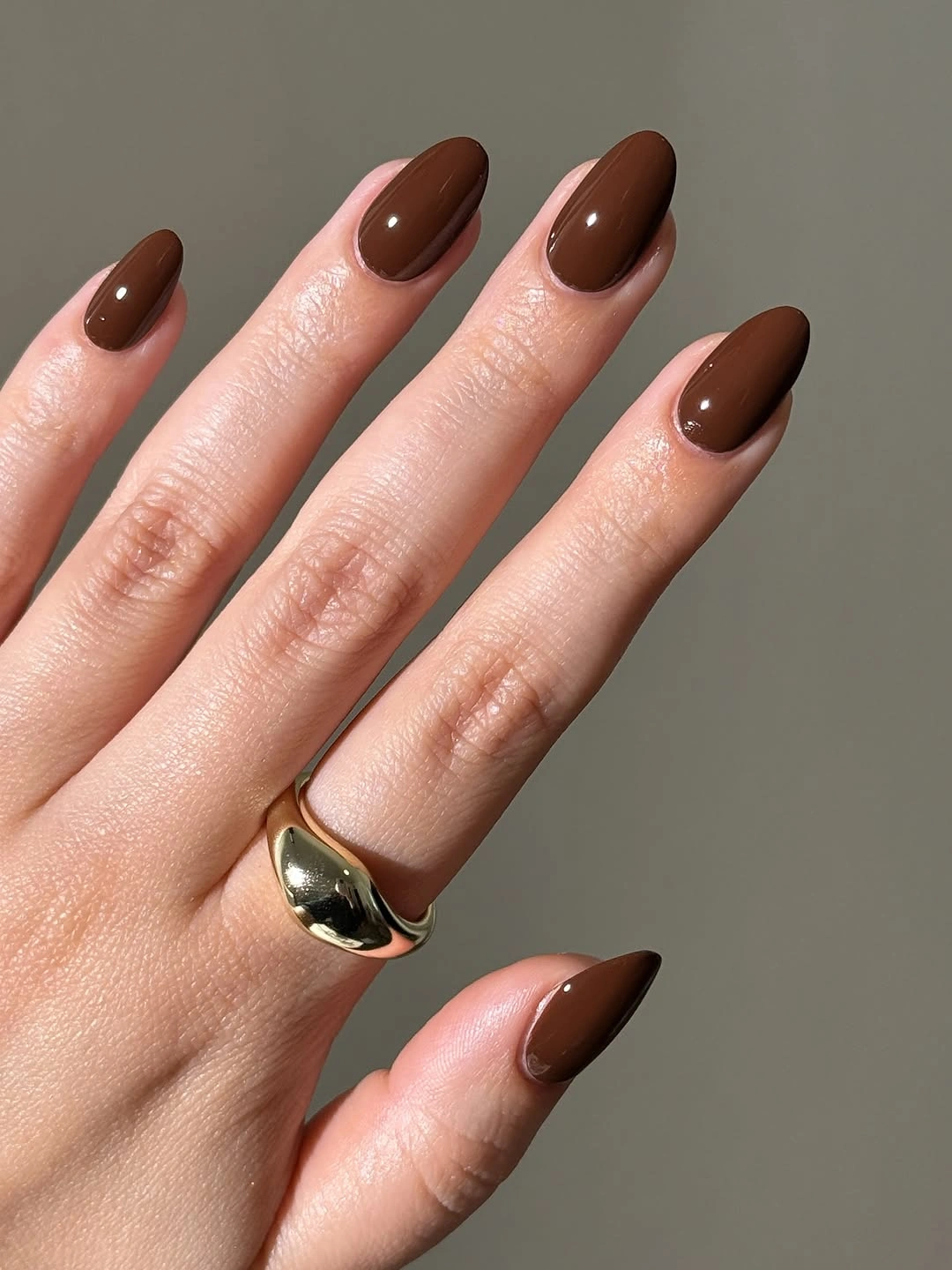 Medium almond nails in a glossy dark brown solid shade