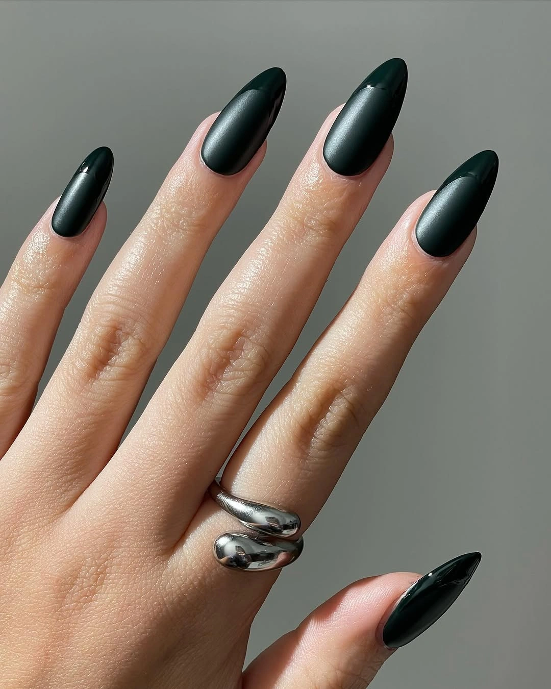 Close view of glossy dark green pointed almond nails