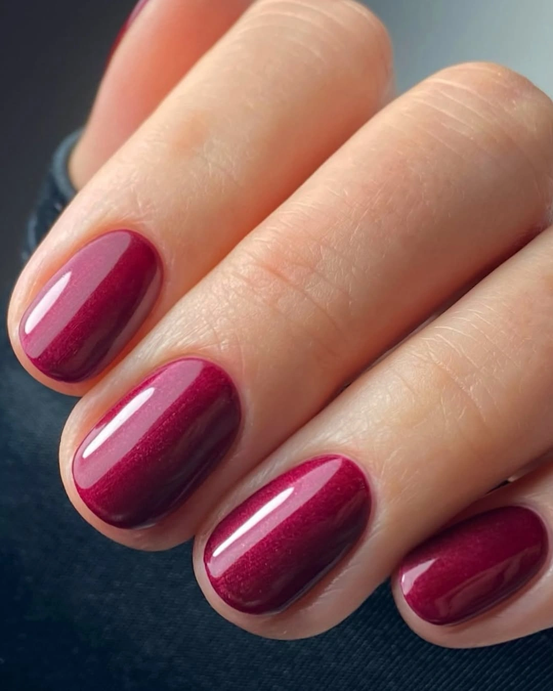 Reflective raspberry wine color on short rounded-square nails