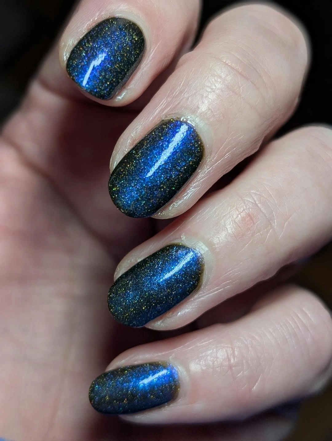 Short blue-green glitter nails with a bright central flash