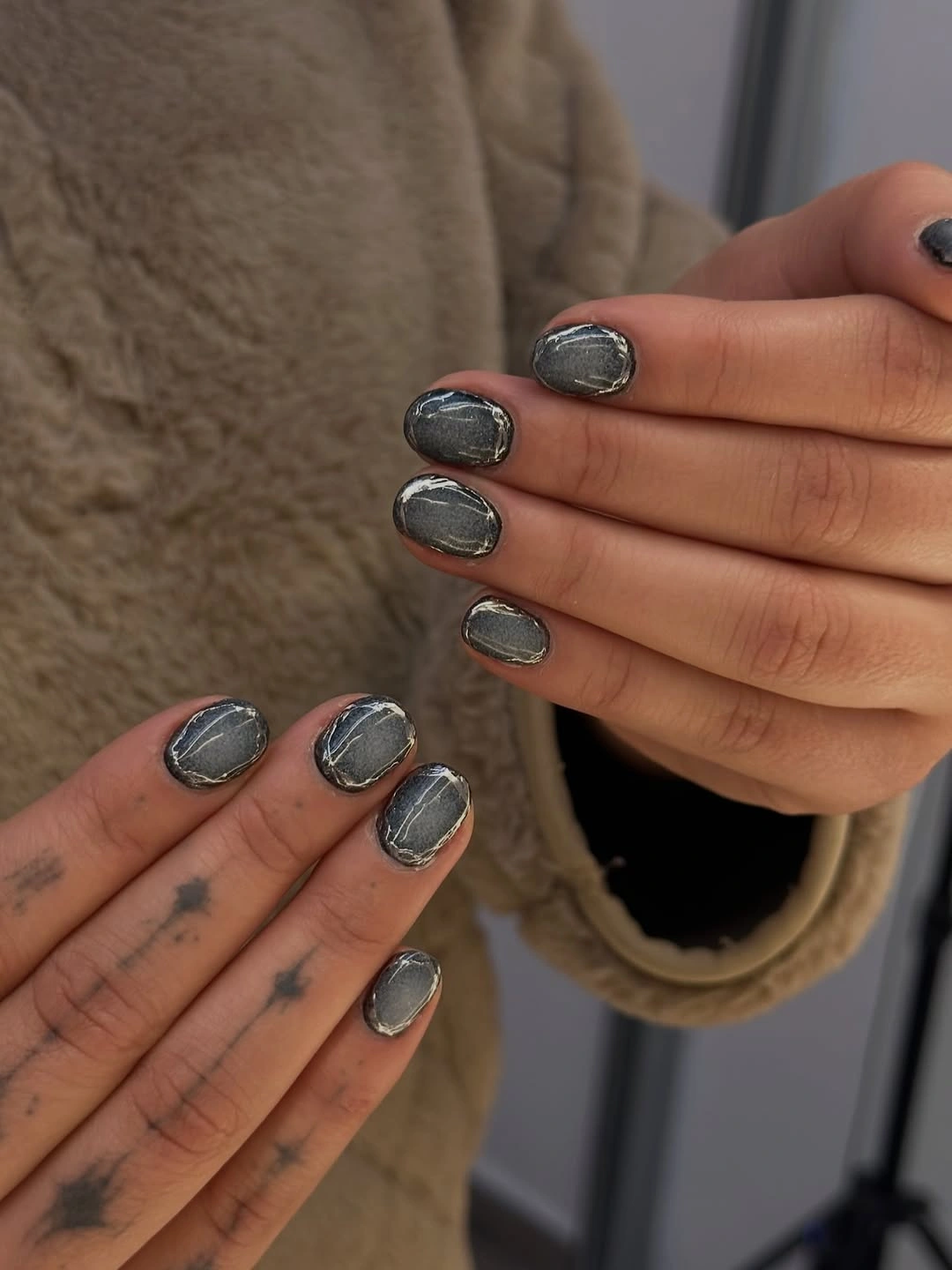 Short rounded silver chrome nails with dark outlines