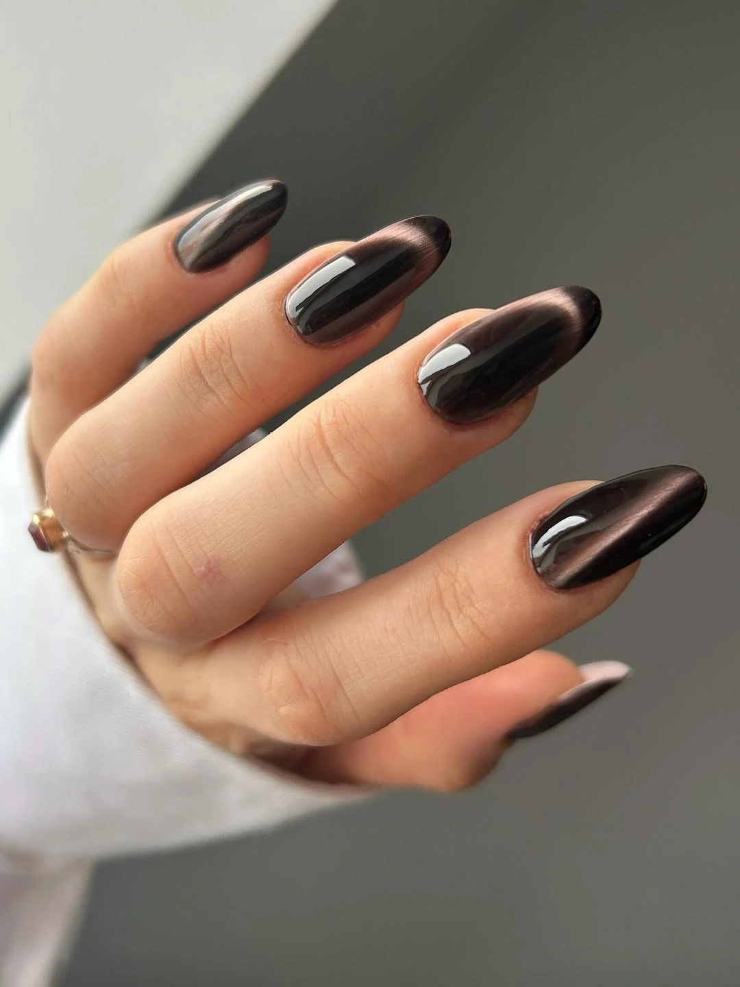 Glossy brown-black almond nails with copper reflections