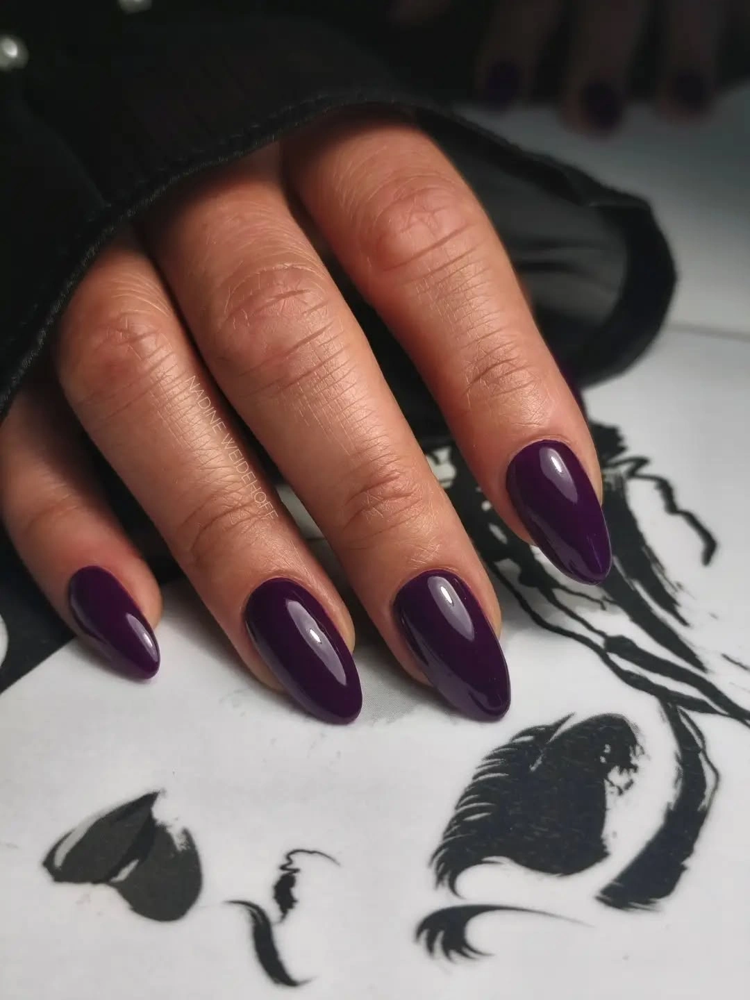 Glossy dark plum almond nails on a compact silhouette