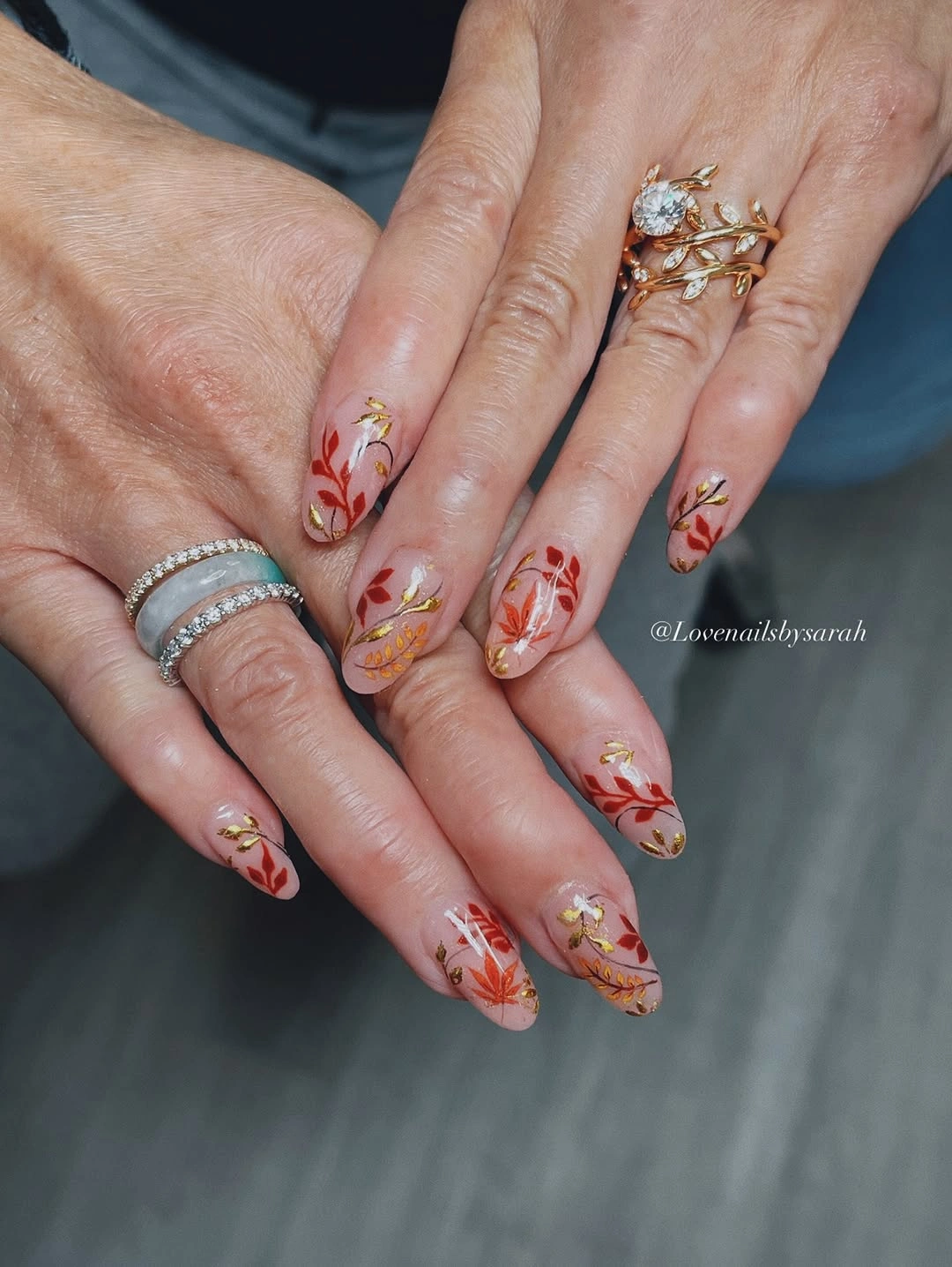 Long almond nails with red orange and gold botanical sprigs