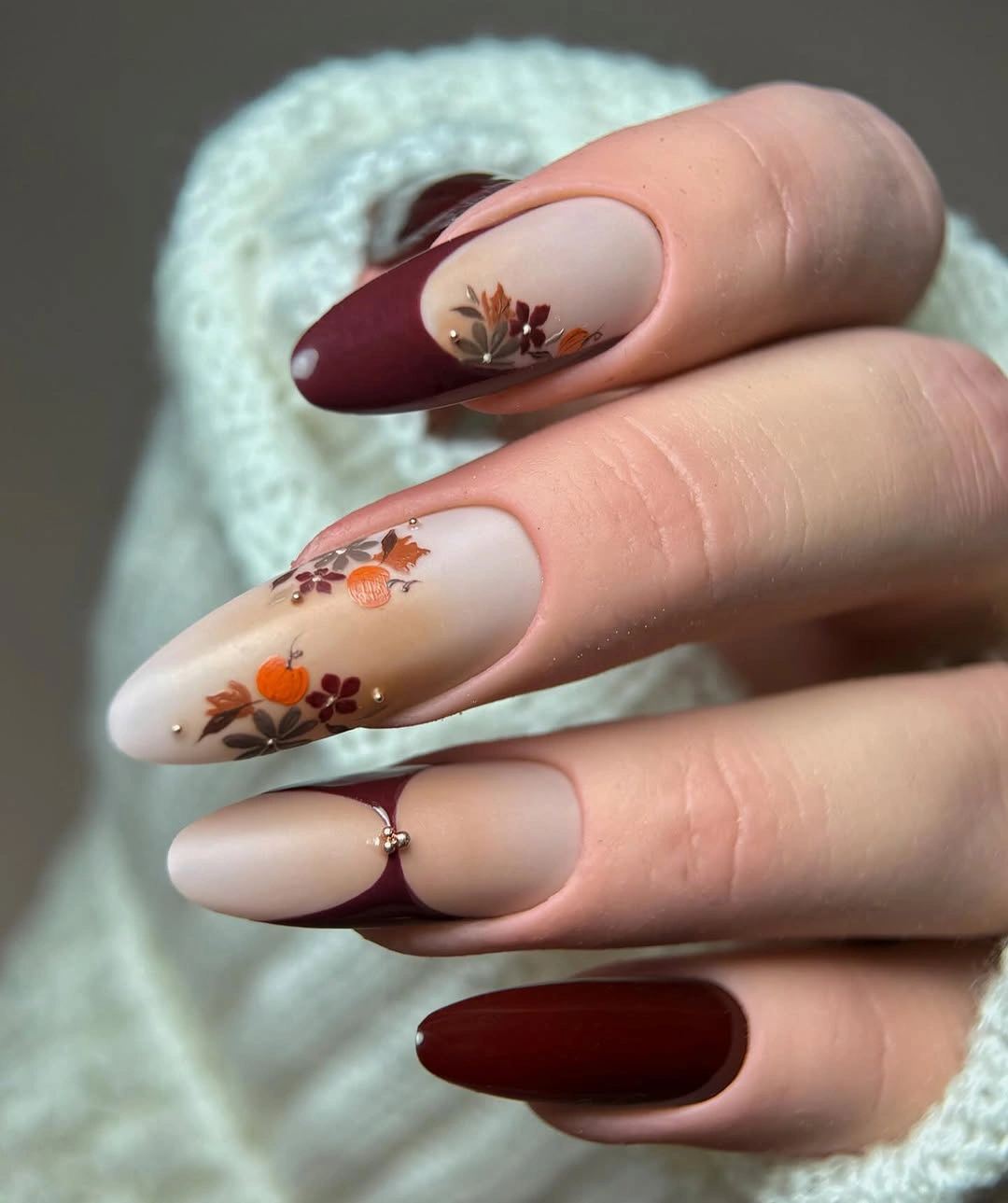 Long almond nails with burgundy tips and autumn flower marks