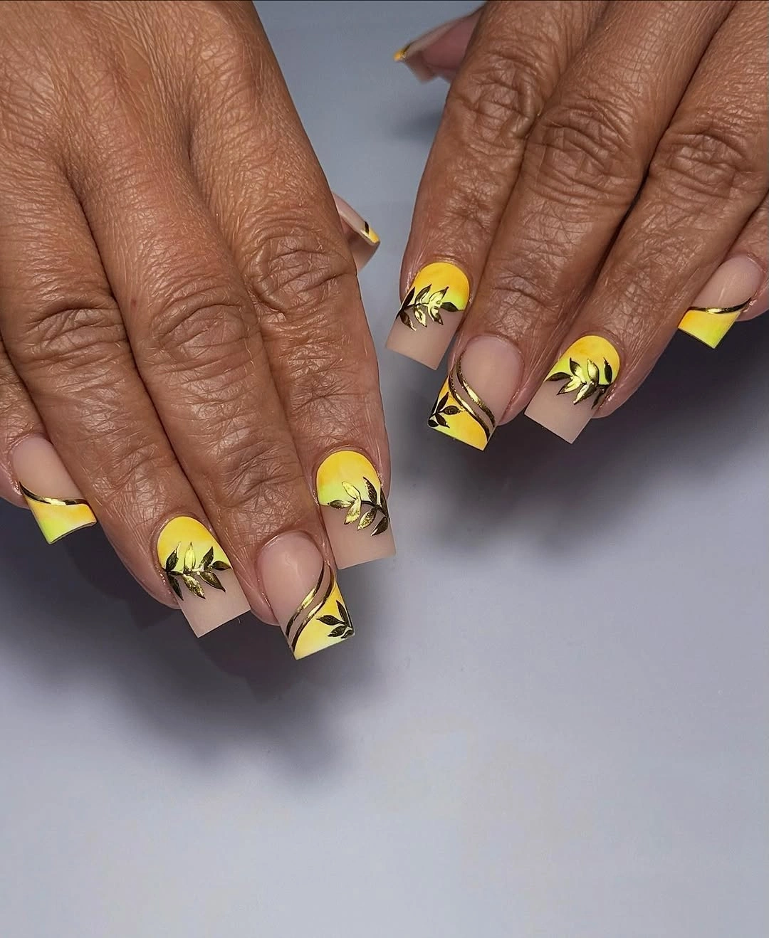 Short square nails with yellow French tips and dark leaf details
