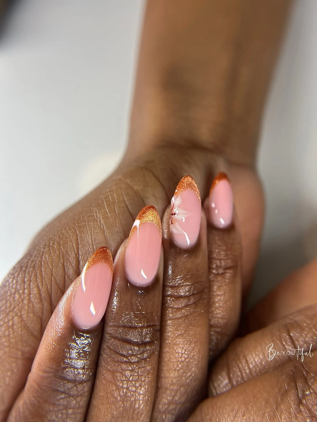 Long almond nails with orange glitter French edges and flowers