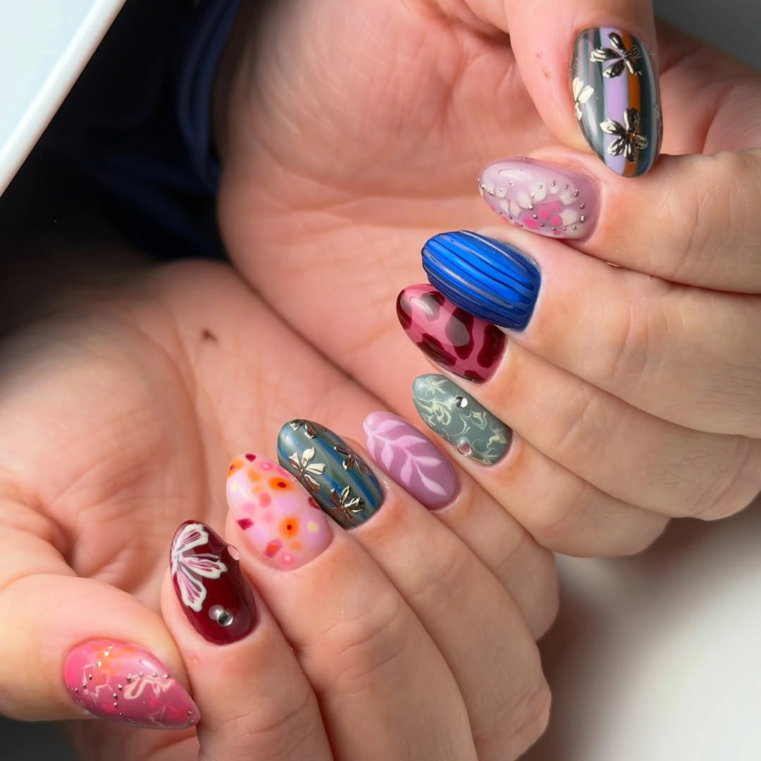 Mixed colorful nails with playful floral dots hearts and metallic details