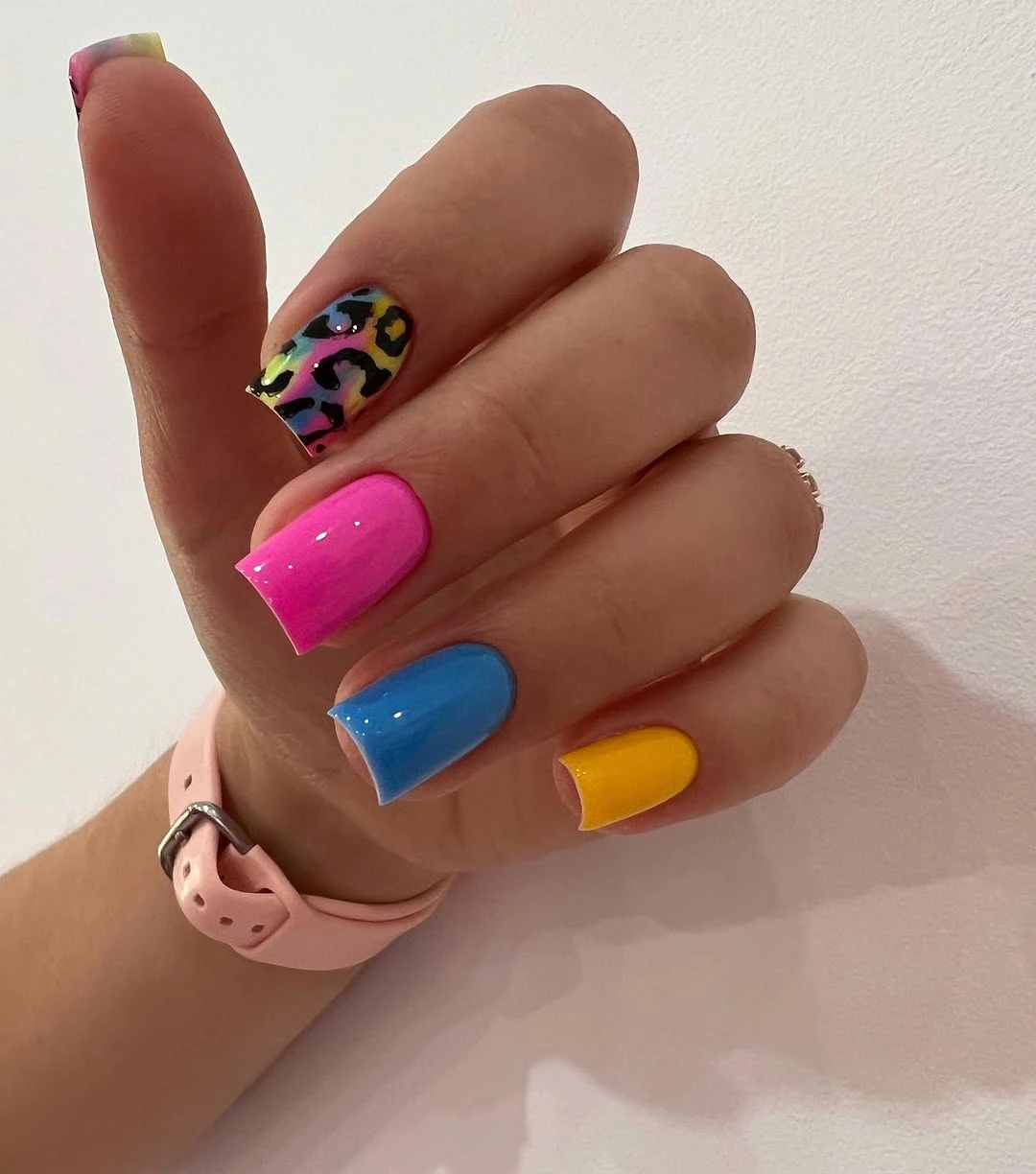 Short square nails in neon pink blue yellow with one patterned accent