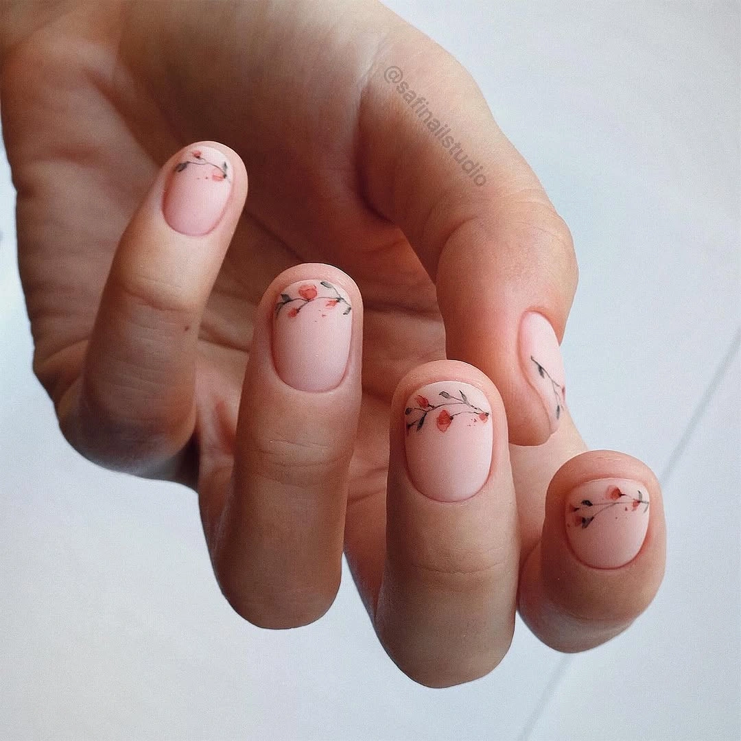 Short nude rounded nails with tiny red botanical accents