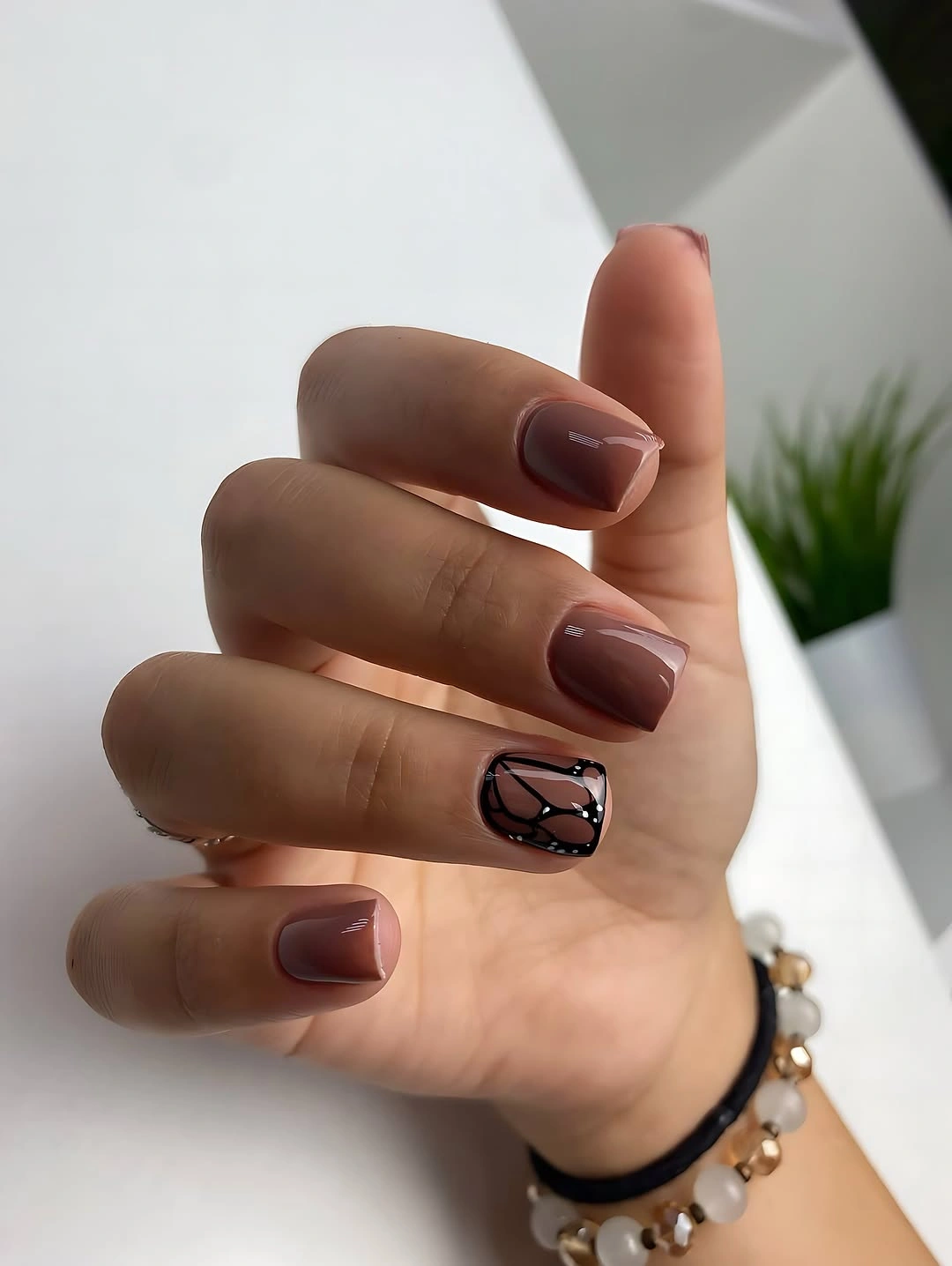 Short brown square nails with one nude outlined accent nail