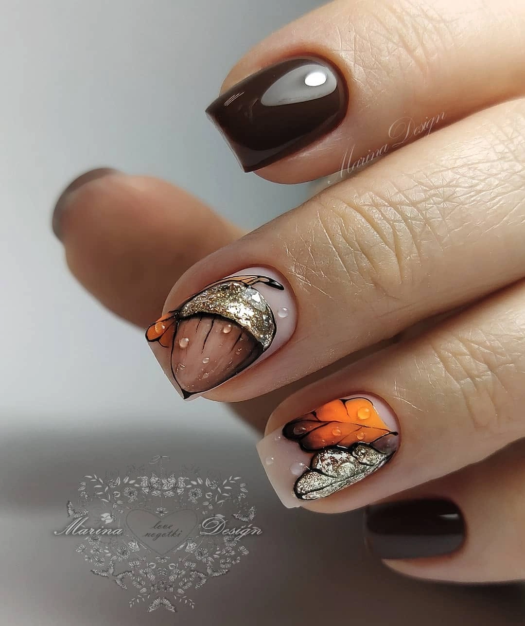 Dark brown short nails with orange accent and glittering border