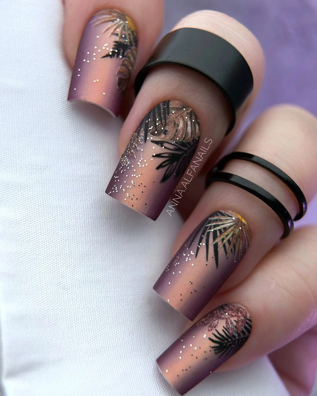 Mauve square nails with dark botanical silhouettes and fine glitter