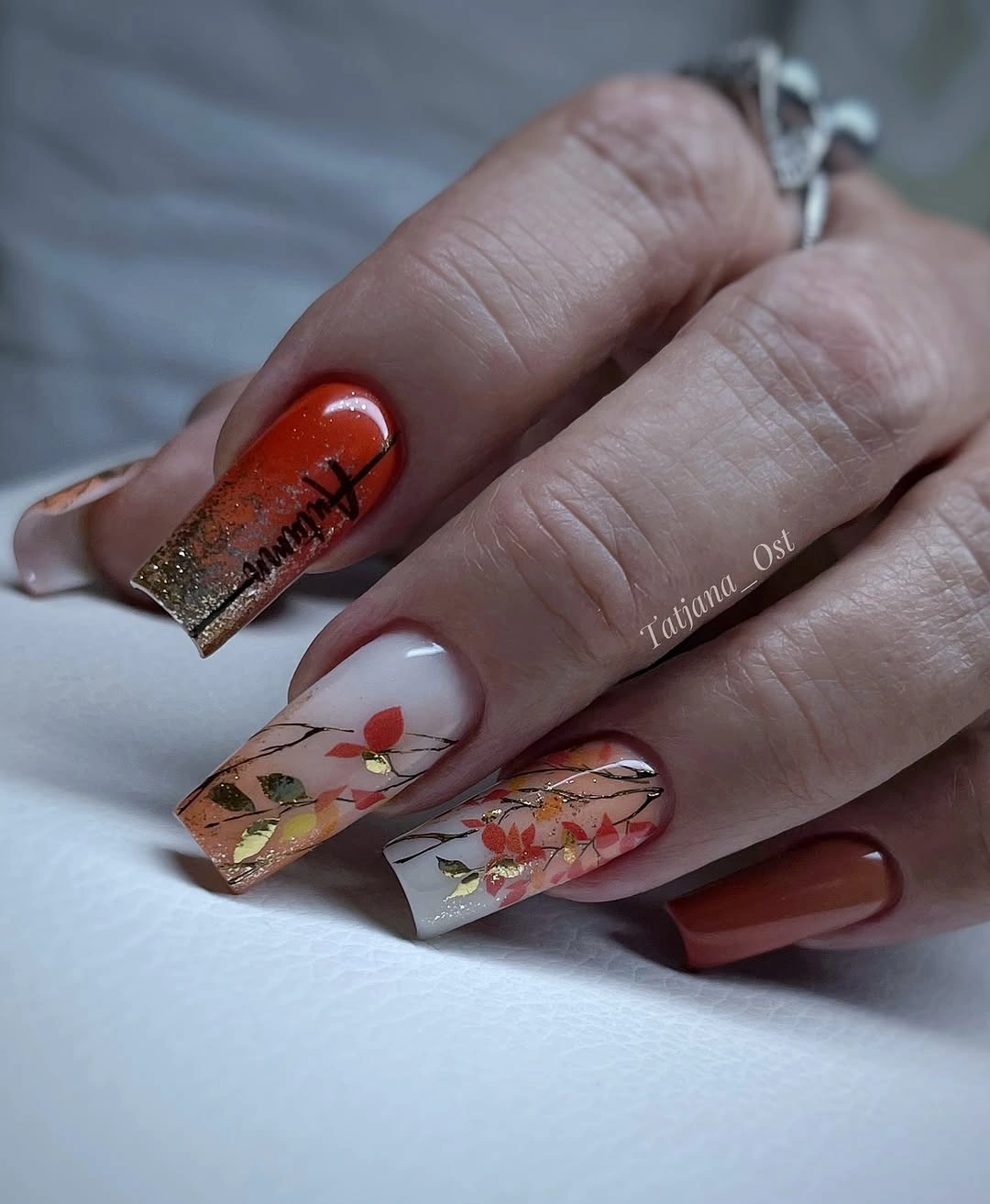 Square nails with brown orange French edges and floral accents