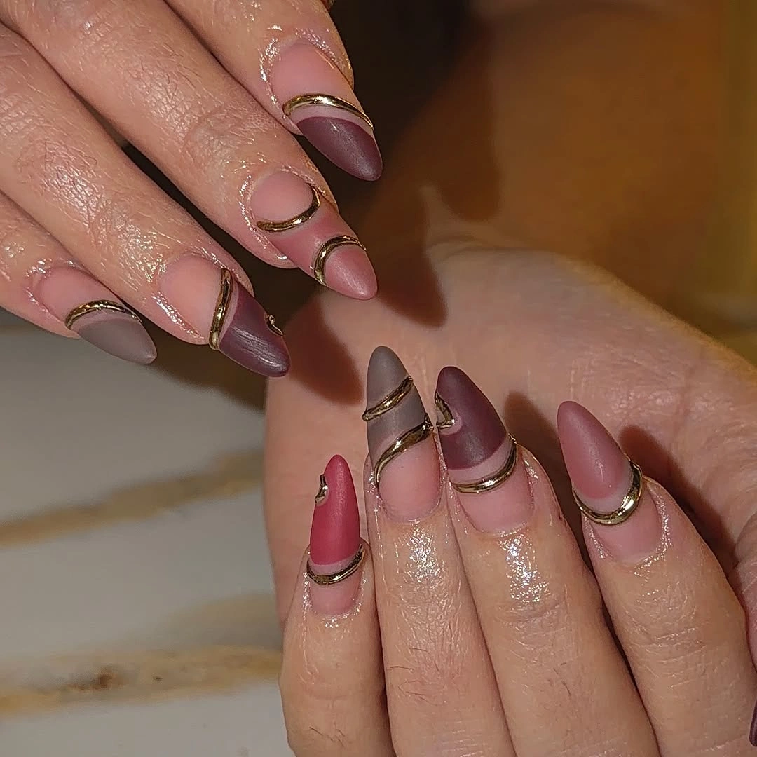 Mauve almond nails with nude space and thin gold curved accents