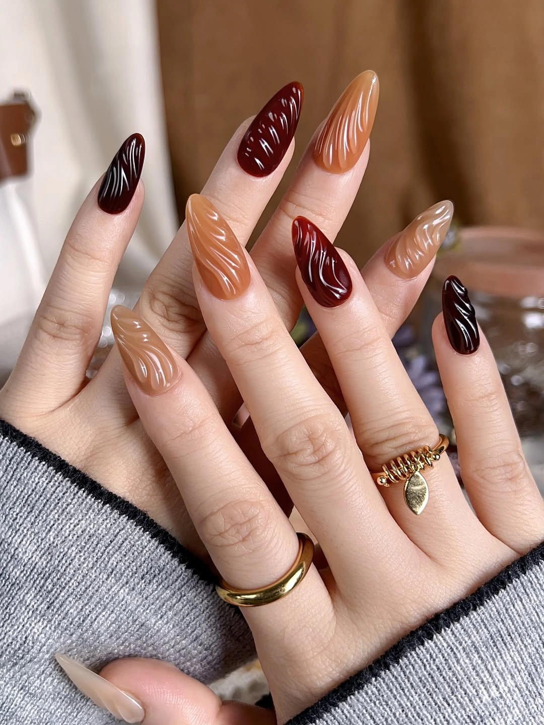 Brown caramel and black almond nails with wavy accent lines