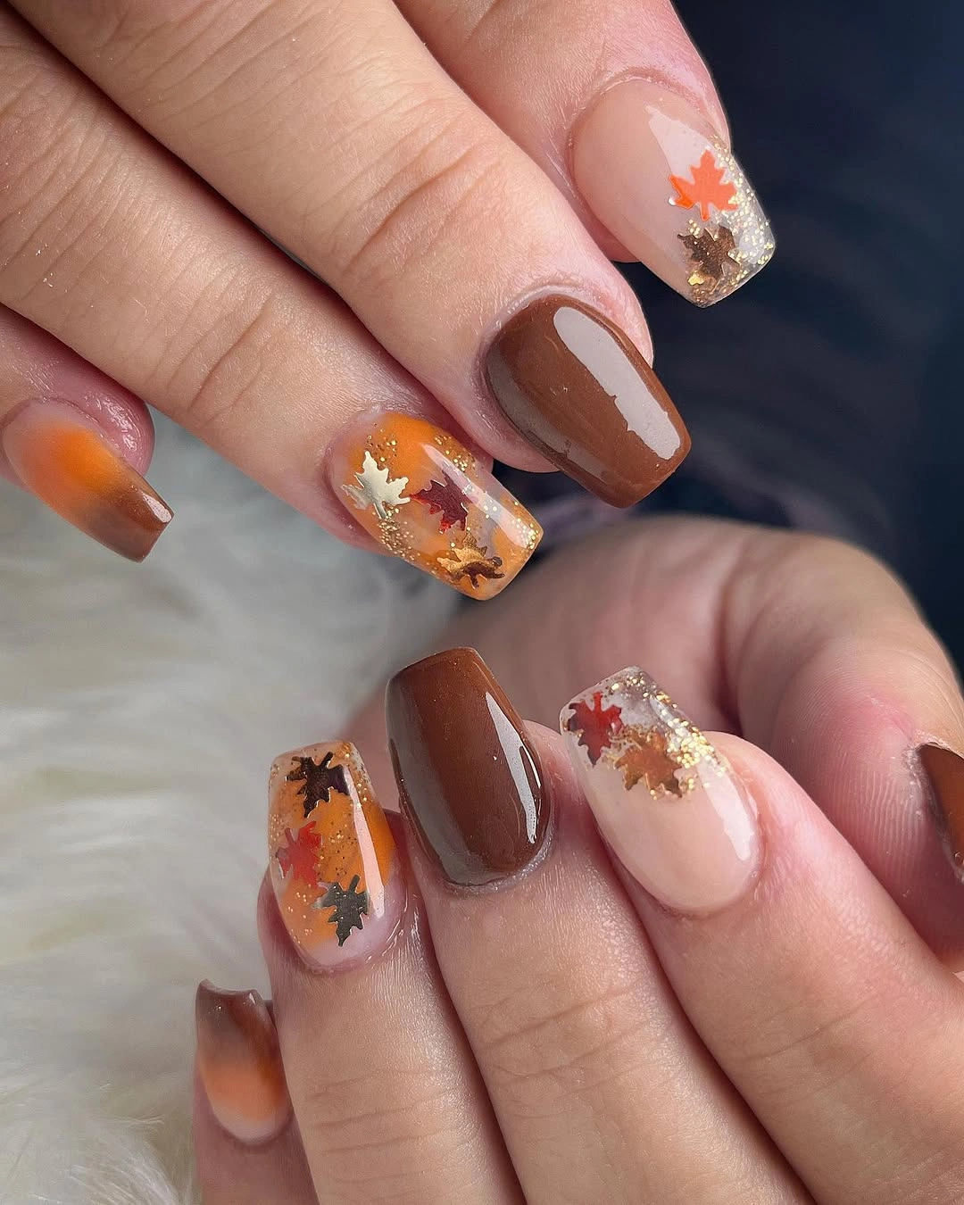 Short cocoa nails with orange maple leaf accents