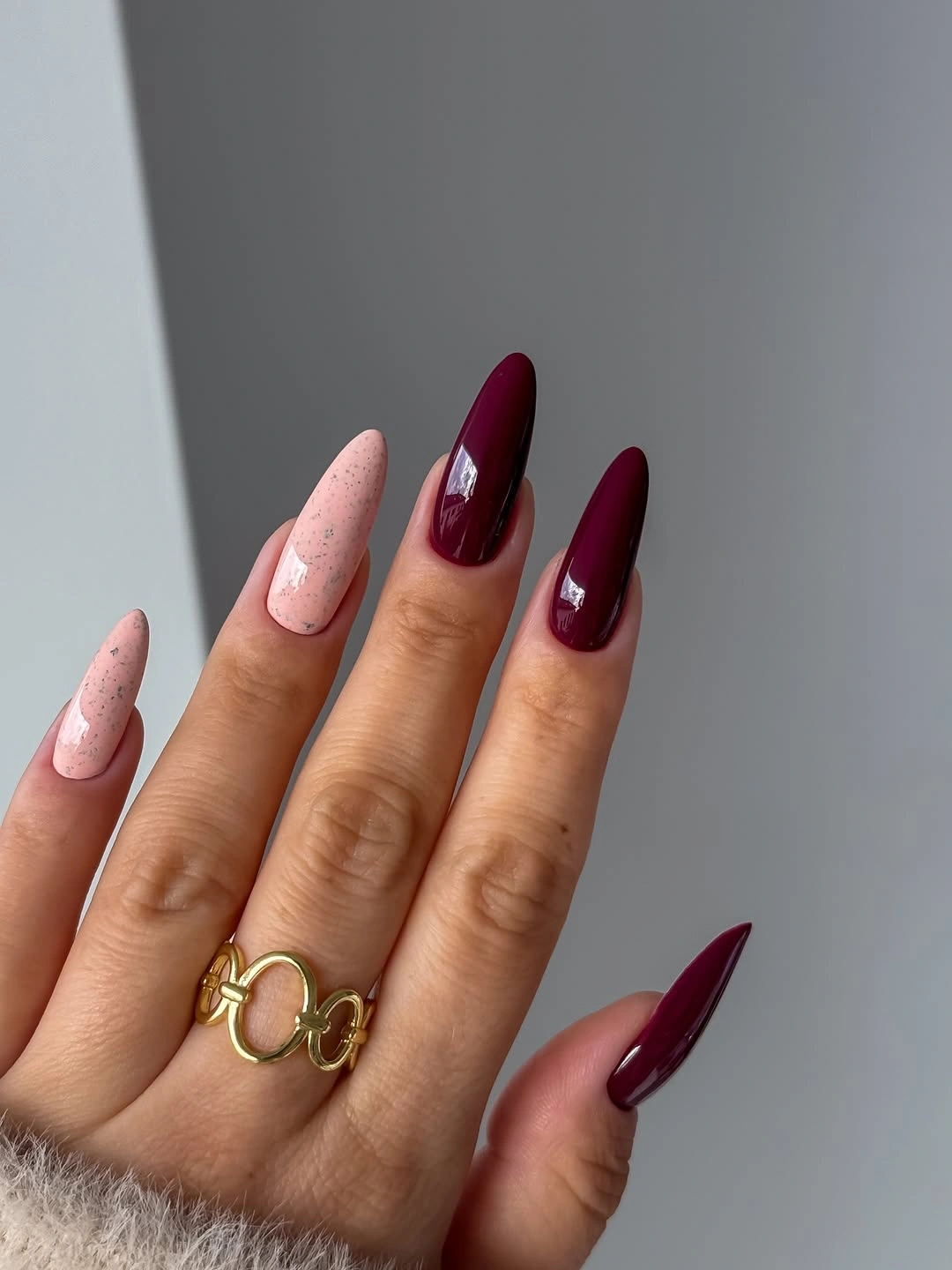 plum burgundy almond nails with speckled pink accents
