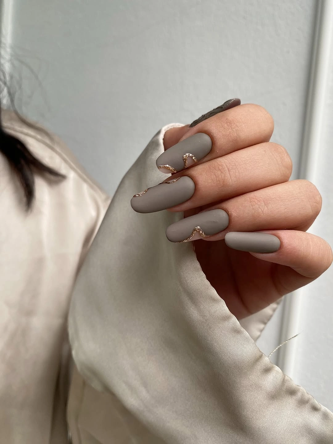 matte taupe almond nails with rose gold wave accents