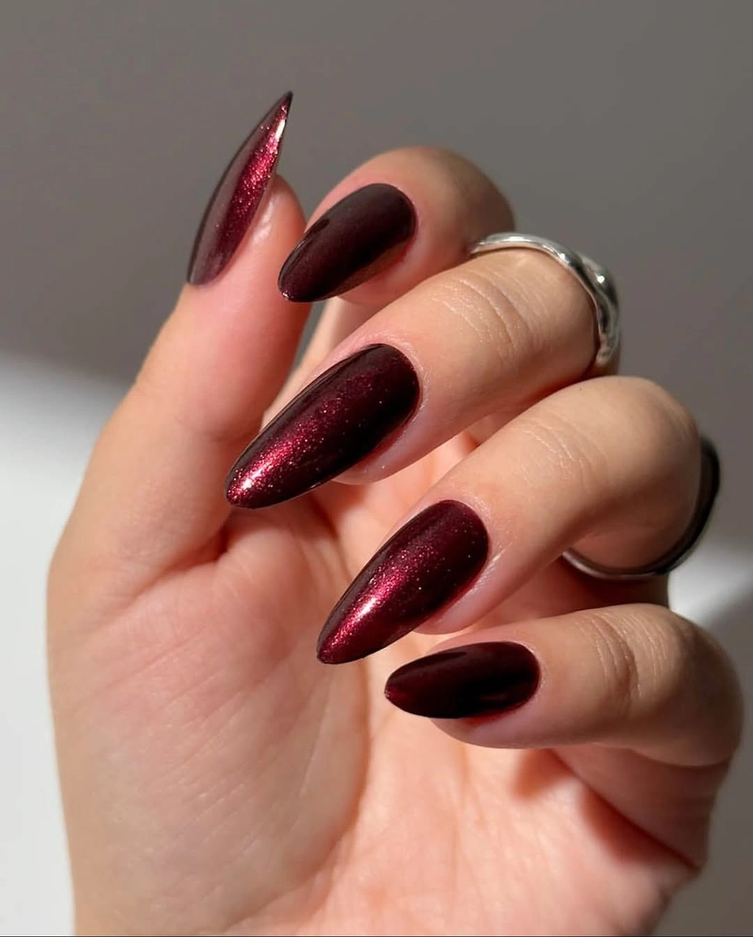 deep burgundy shimmer almond nails in glossy finish