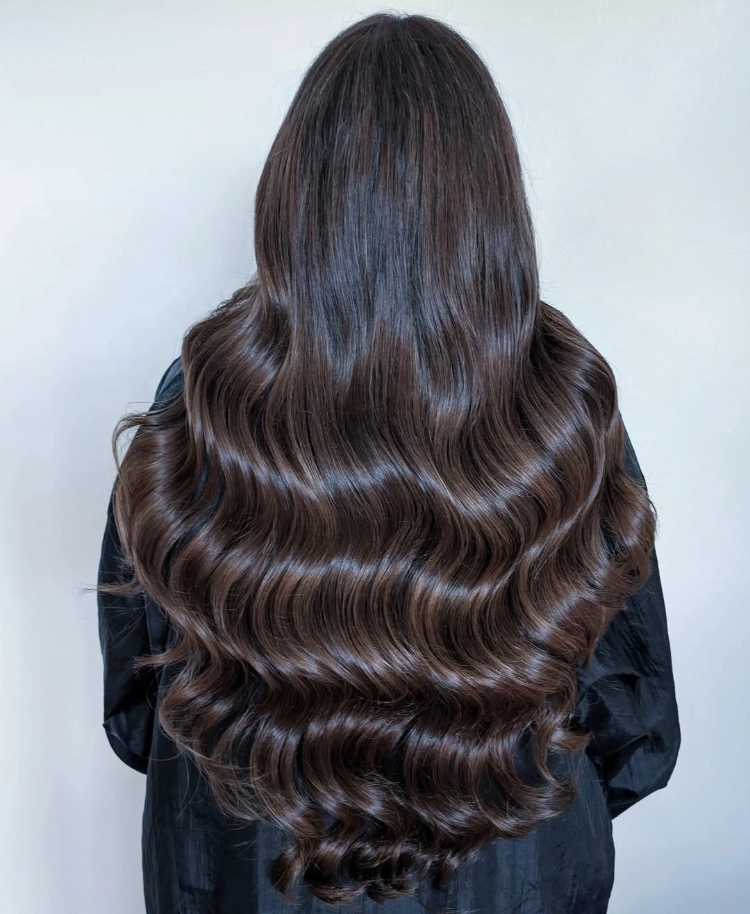Deep chocolate brown hair in long glossy rounded waves