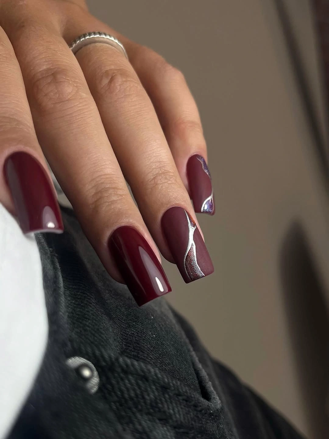 Long square burgundy nails with a single silver curve