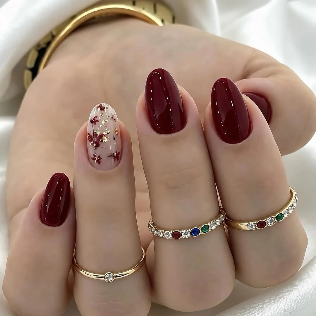 Short burgundy rounded nails with sheer floral gold accent