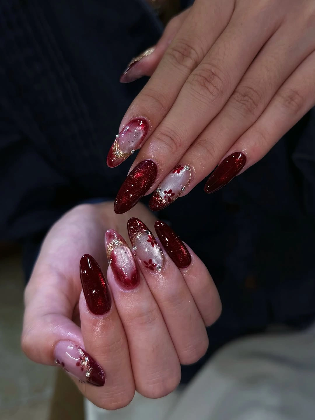 Long almond burgundy glitter nails with floral gold accents