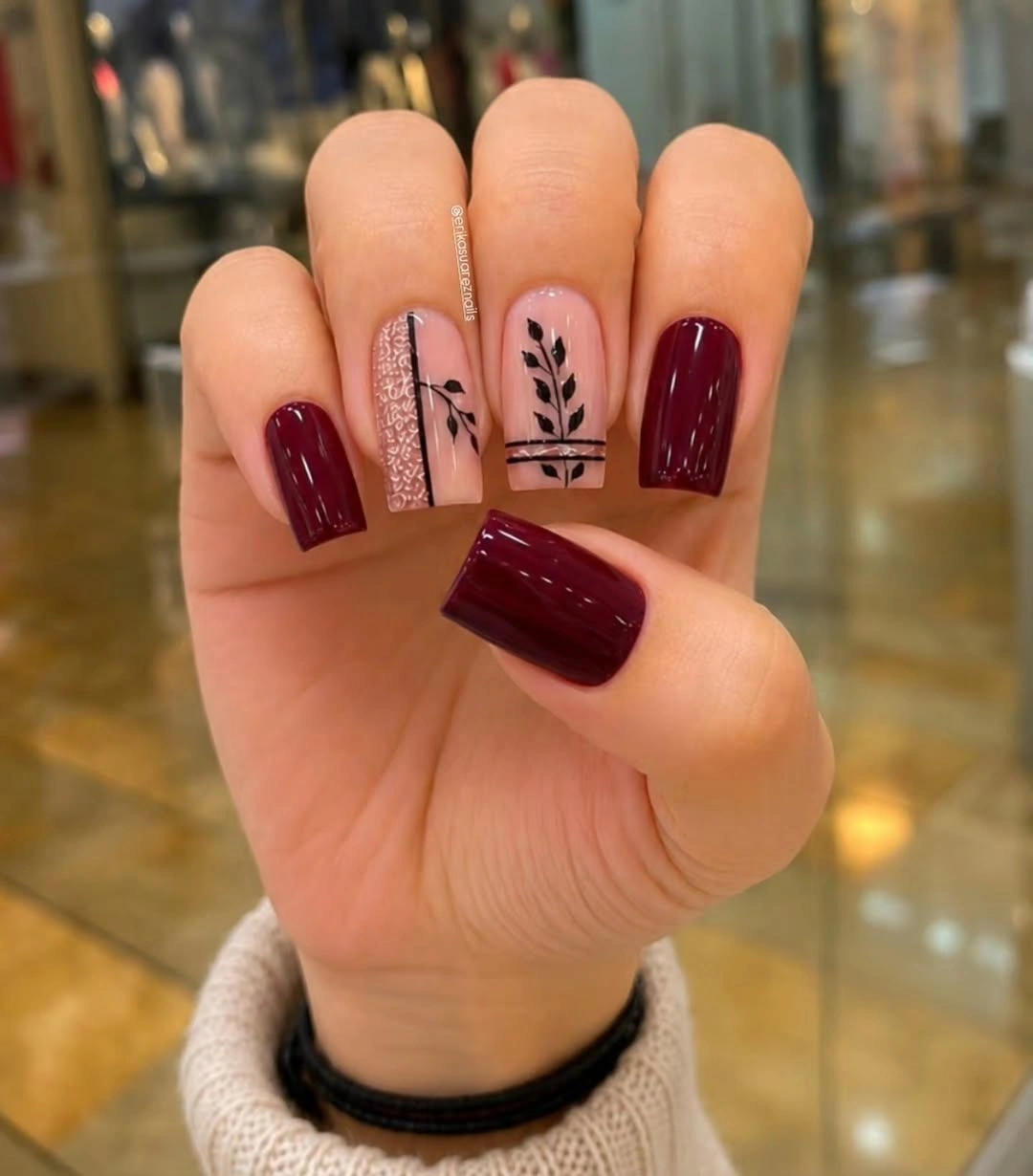 Short square burgundy nails with nude botanical line art