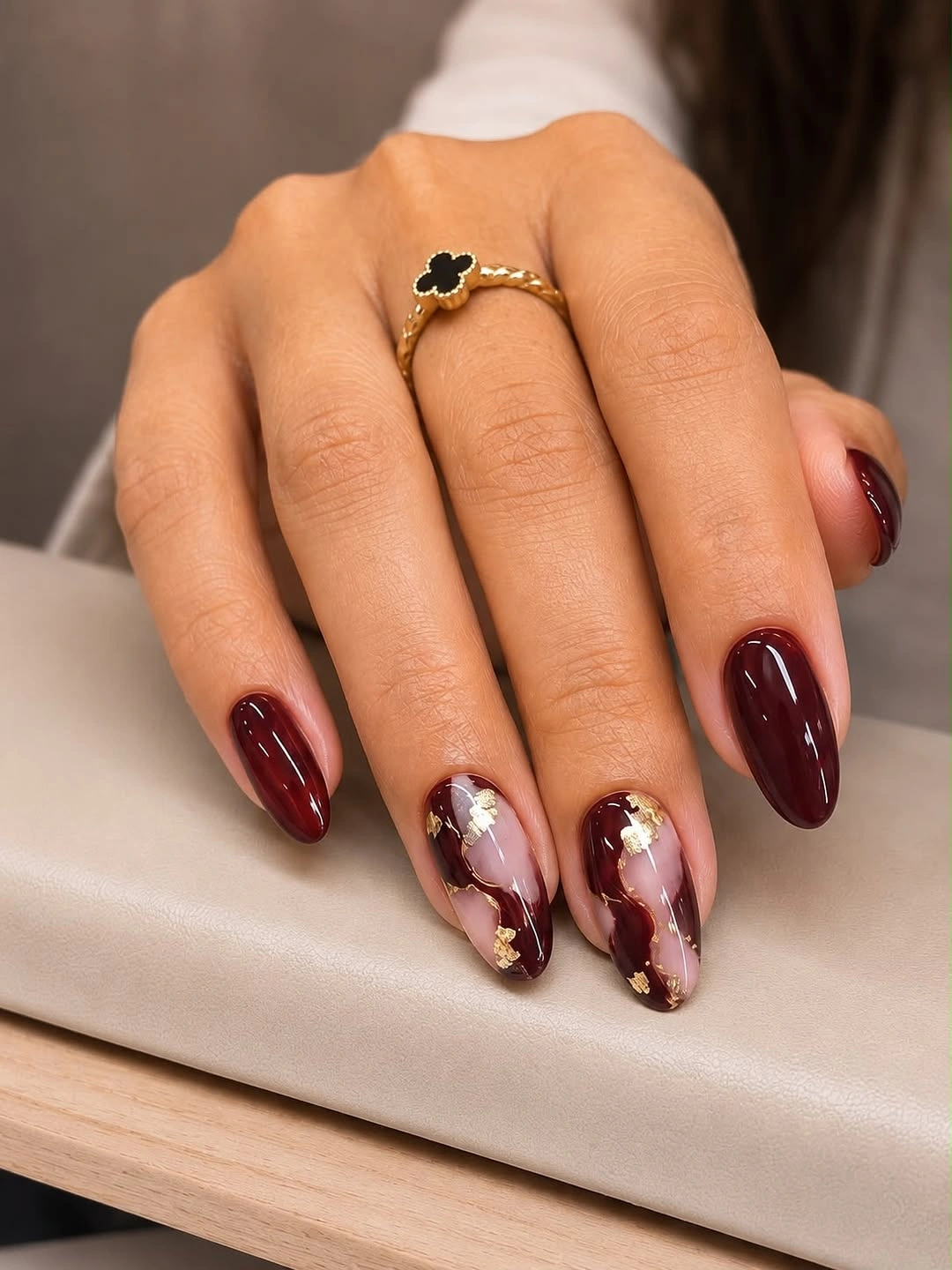Medium almond burgundy nails with nude floral gold foil accents