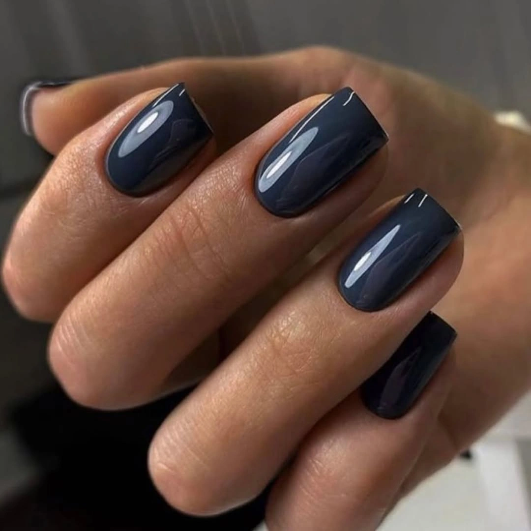 Short rounded navy nails with a clean glossy finish