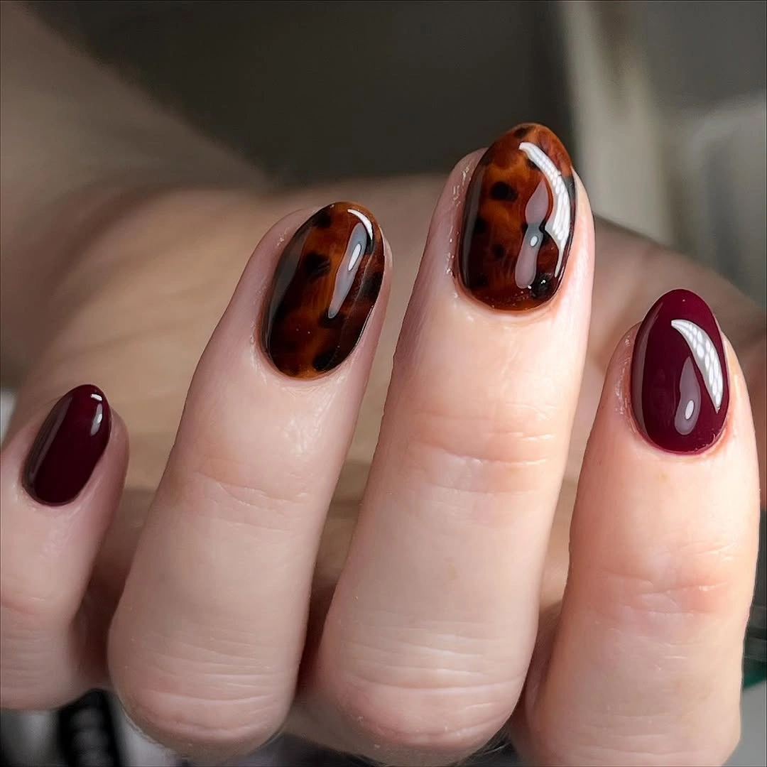 Short oval brown patterned nails with burgundy accents