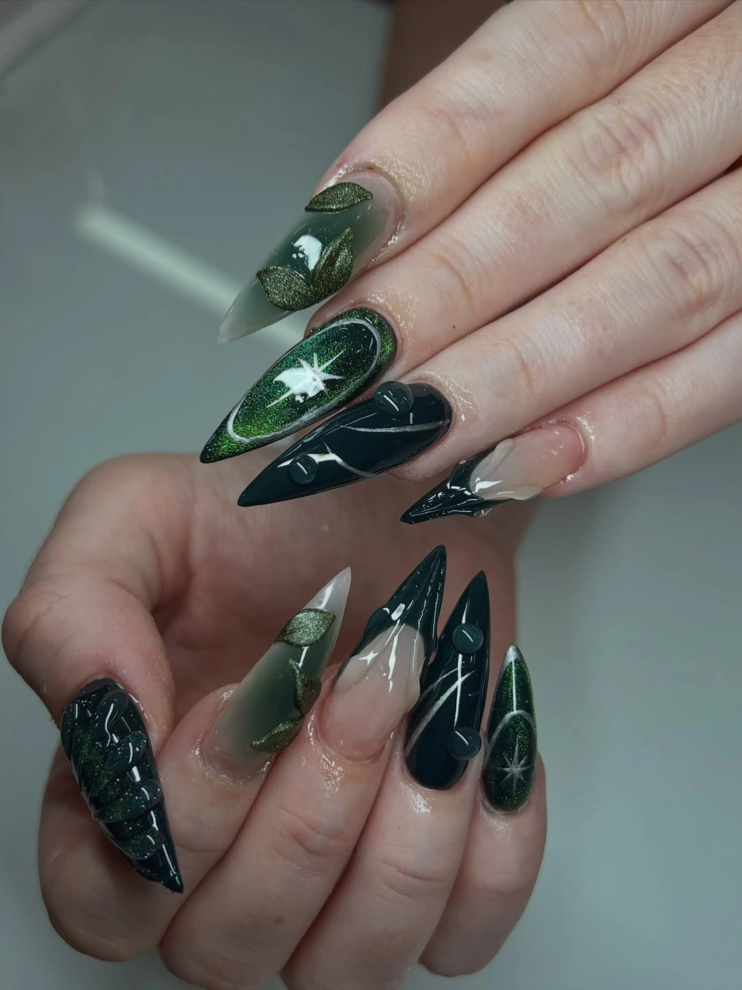 Long pointed forest green nails with dark botanical accents