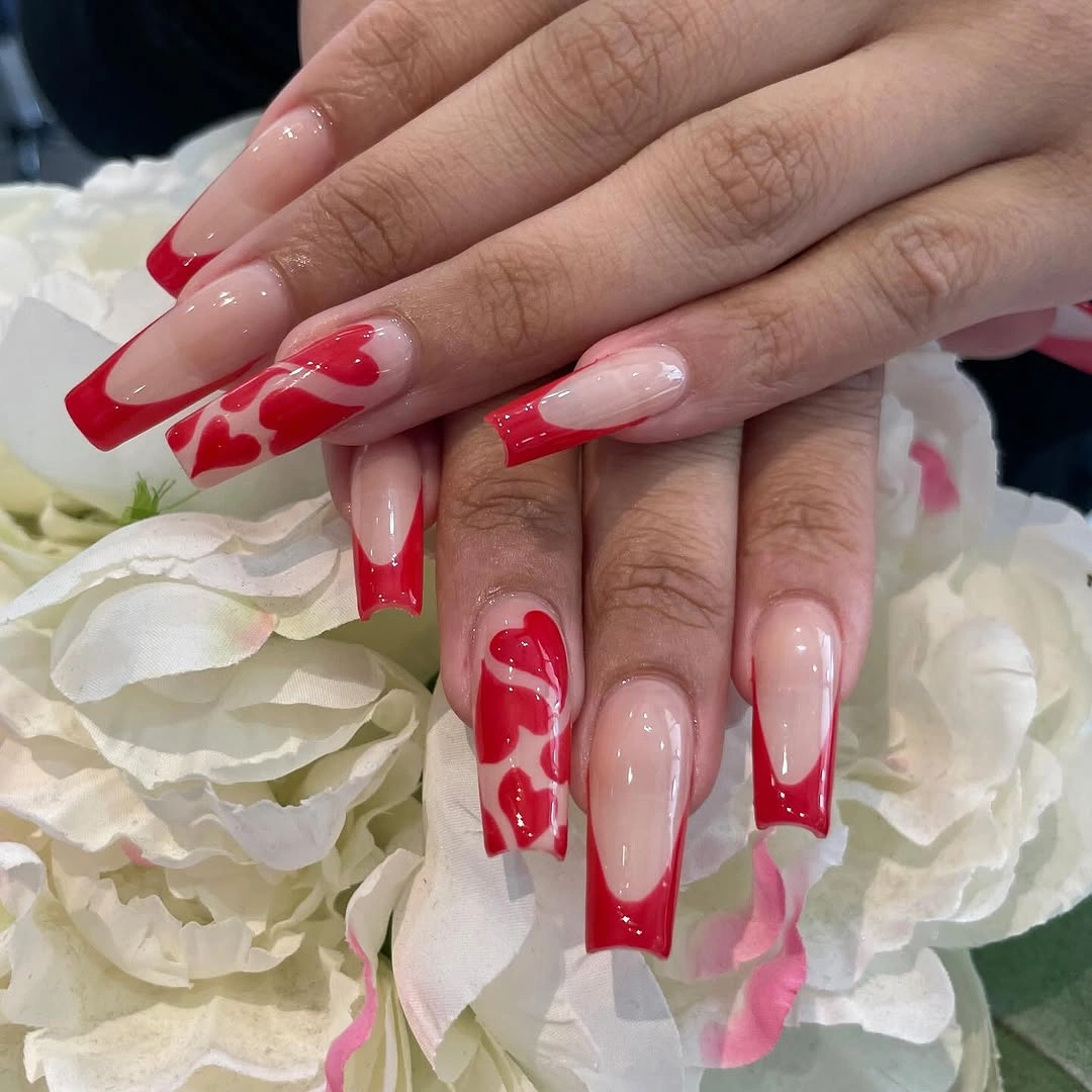 Pale nude almond nails with vivid red sweeping curved tip accents