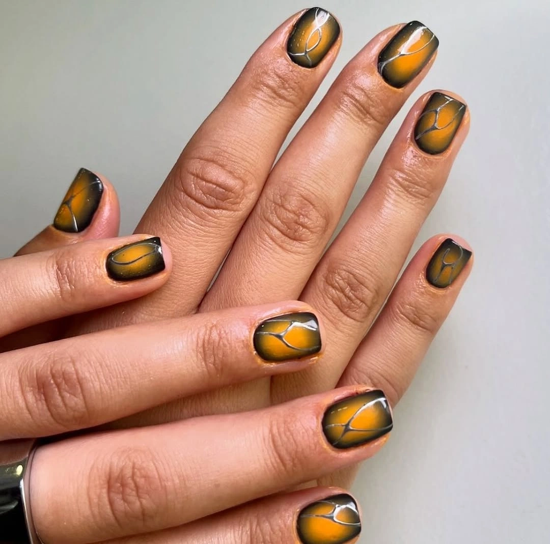 Short square nails with warm orange smoky black rounded graphic shapes and fine curves